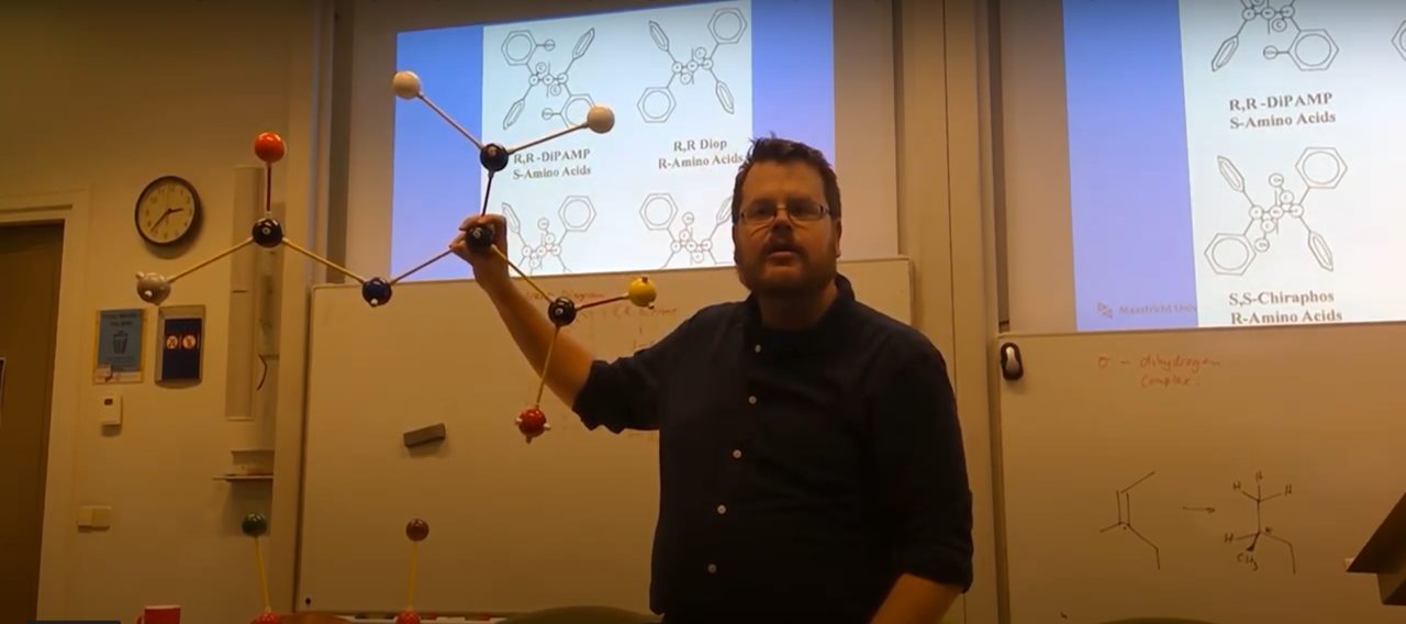 Dr Blom explaining molecular structures with a model during a chemistry lecture
